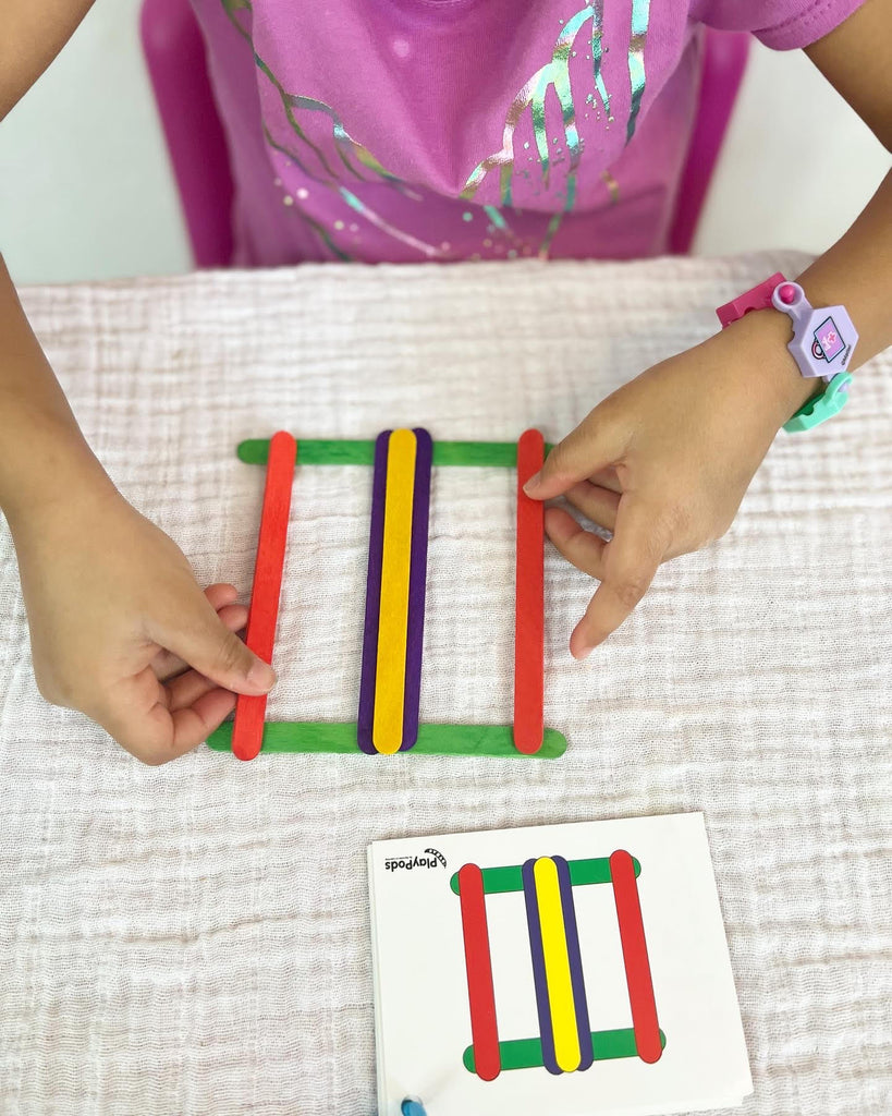 Little girl arranging sticks to follow pattern on card