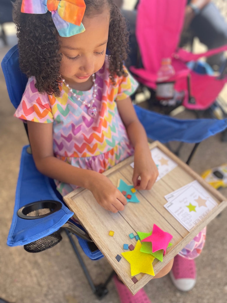Little girl in colorful dress putting sprinkle tiles on felt star