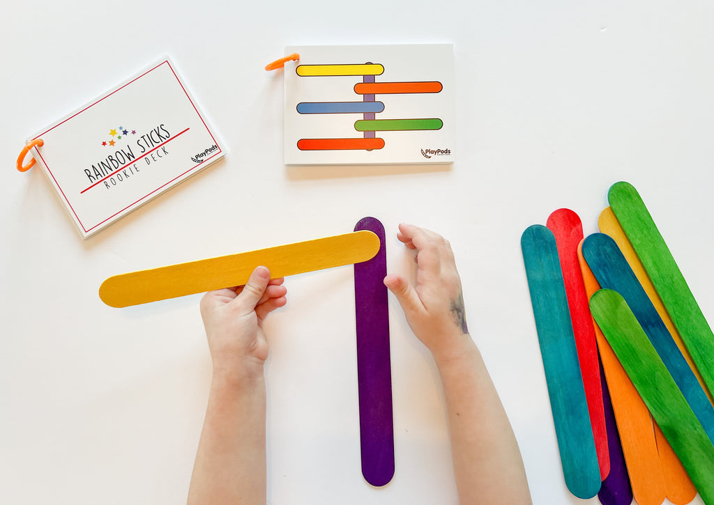 Childs hands using colorful jumbo sticks to follow pattern on card