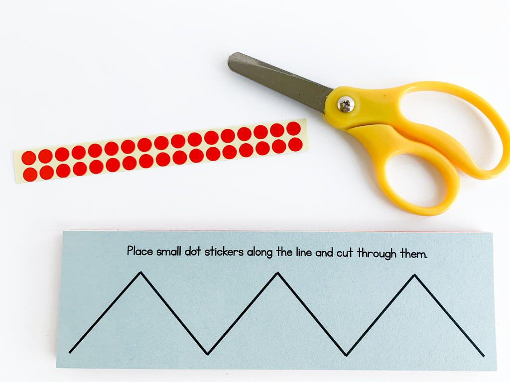 Yellow scissors, red dot stickers, and zig zag line on paper 