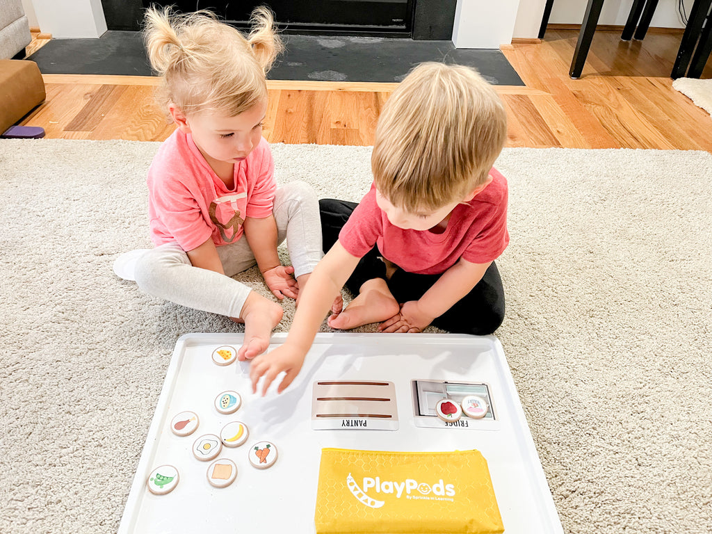 Little girl and boy putting food image discs on activity cards