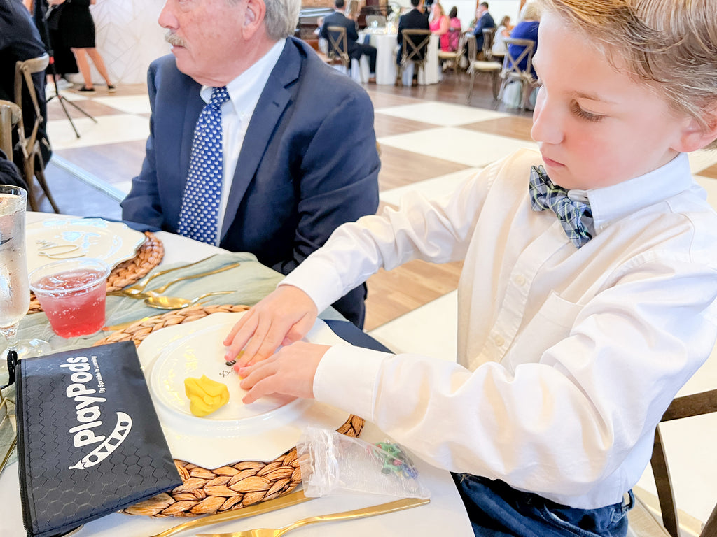 Little boy in dress clothes playing with activity dough at an event