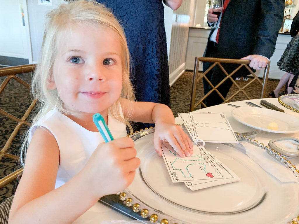 Happy girl tracing lines on activity cards at a wedding reception